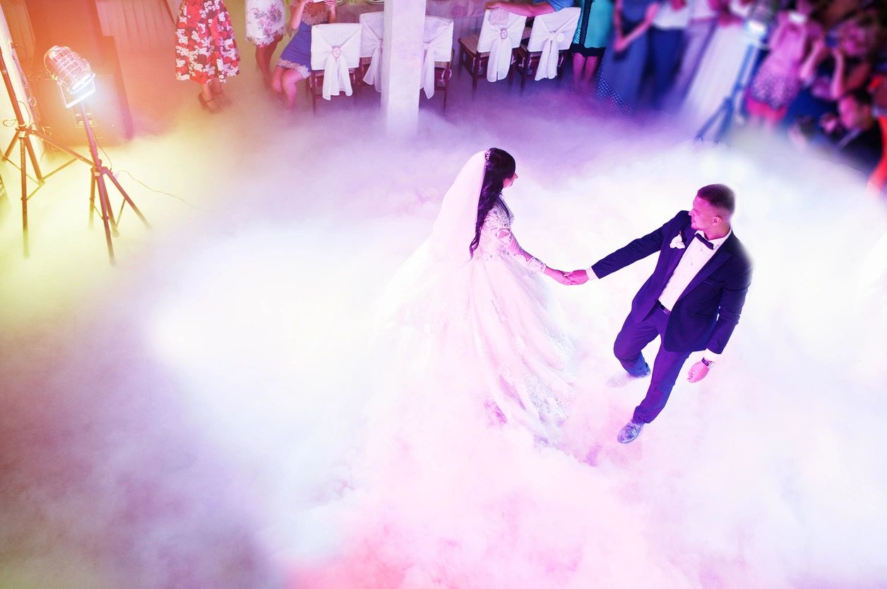 Amazing first wedding dance of newlywed with different colourful light and heavy smoke on restaurant. View from above with guests. (Amazing first wedding dance of newlywed with different colourful light and heavy smoke on restaurant. View from above w